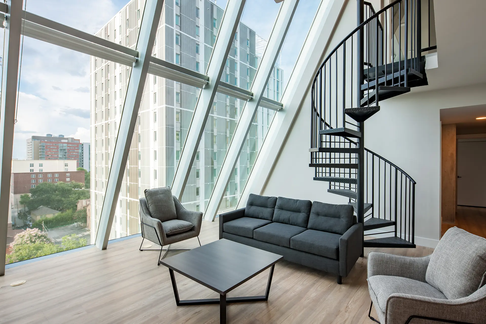 luxury two-story student apartment with spiral staircase and sloped floor to ceiling windows.